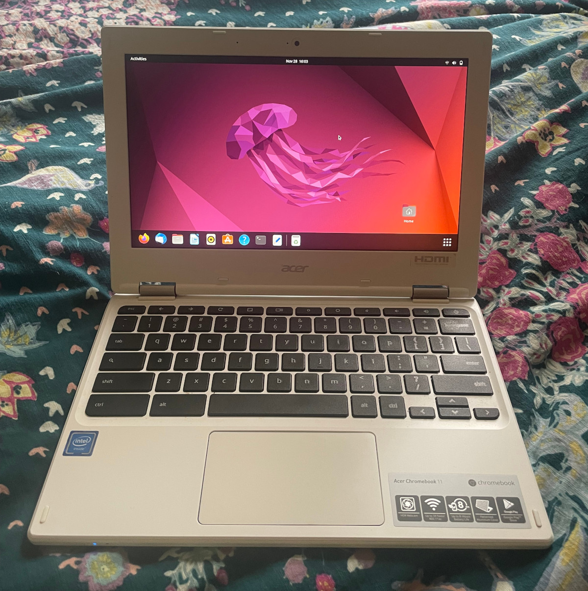 Chromebook on a bed displaying Ubuntu home screen