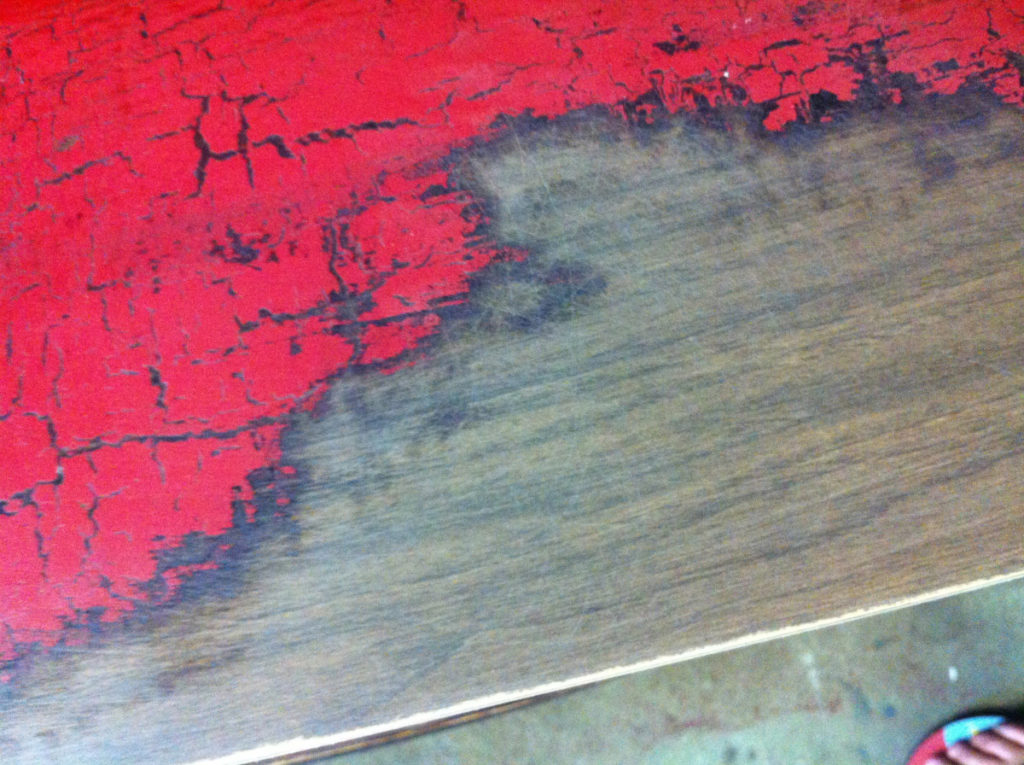 Top of a desk with crappy red paint and bare wood underneath