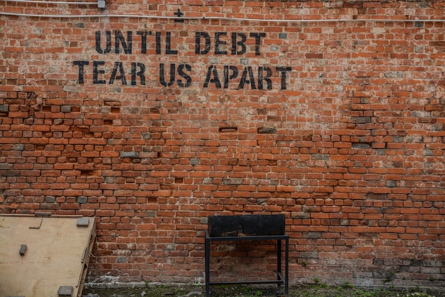 Brick wall that reads, Until Debt Tear Us Apart.