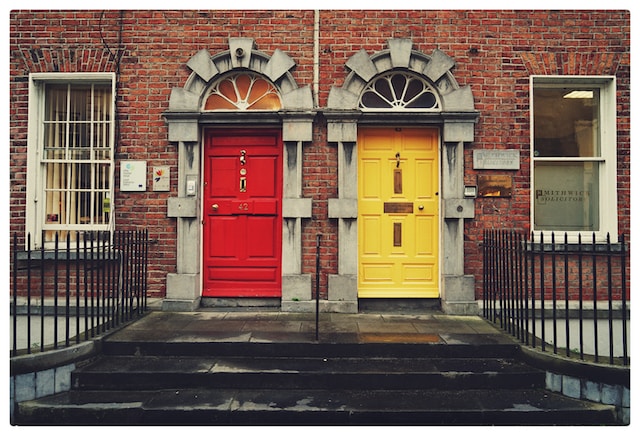 A brick building with a red door on the left and a yellow door on the right